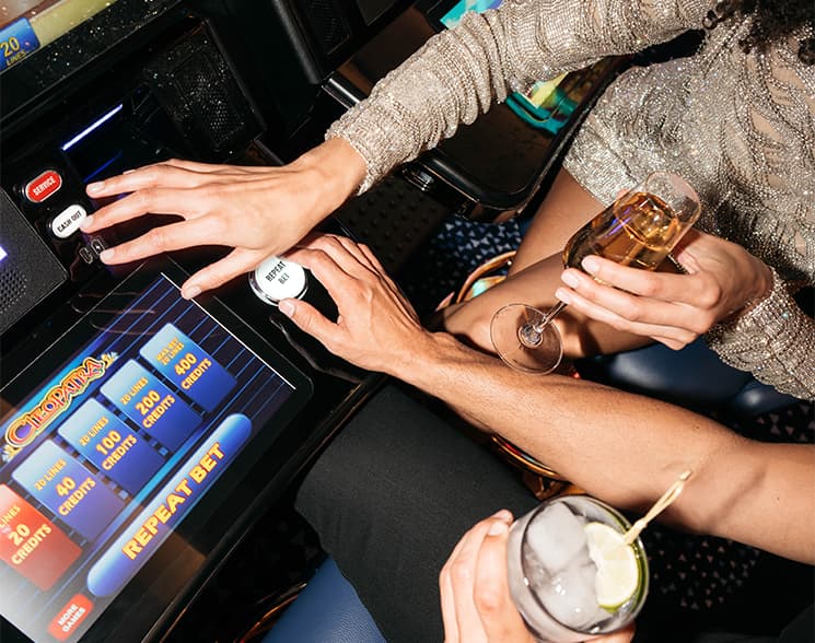 Hands reaching over a slot machine and holding a glass of champagne