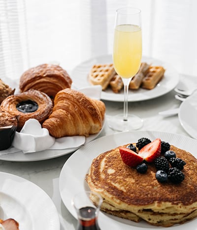 Plates of pancakes, croissants, waffles and a mimosa for room service at Fontainebleau Las Vegas