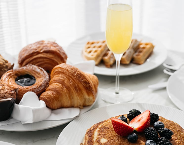 Plates of pancakes, croissants, waffles and a mimosa for room service at Fontainebleau Las Vegas
