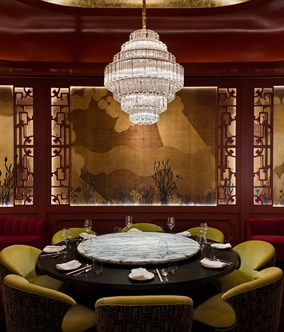 Restaurant dining space with green chairs, red walls under a chandelier at Chyna Club restaurant