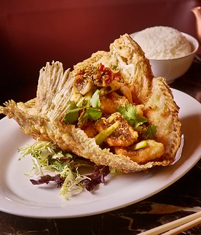 Plate of crispy fish surrounded by decor from Chyna Club restaurant