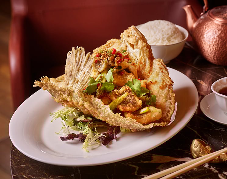 Plate of crispy fish surrounded by decor from Chyna Club restaurant