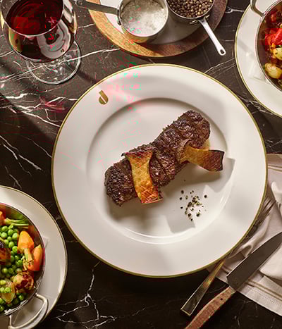 Steak on white plate with full table of accoutrements from Don's Prime