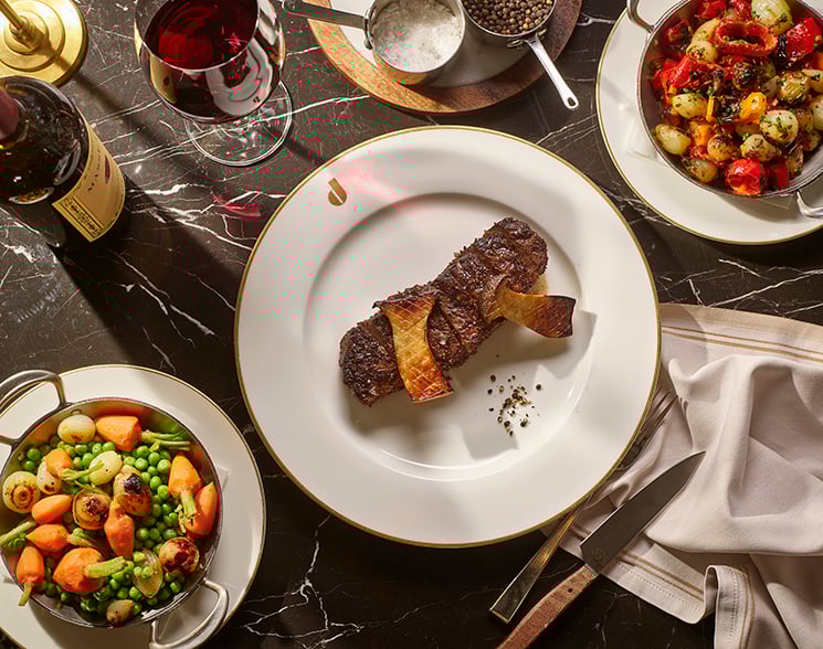 Steak on white plate with full table of accoutrements from Don's Prime