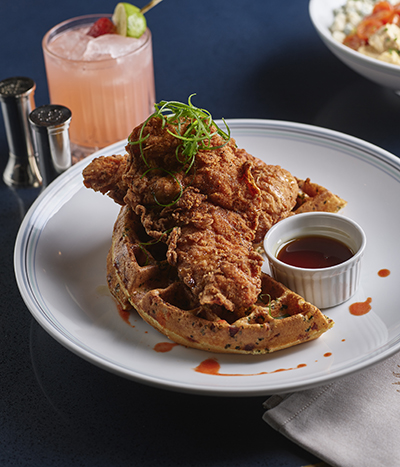 Plate of chicken and waffles on a white plate on a blue table in Vida