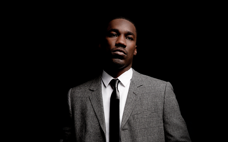 Giveon in a suit in front of a dark background