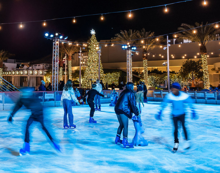 People ice skating with holiday decorations in the background
