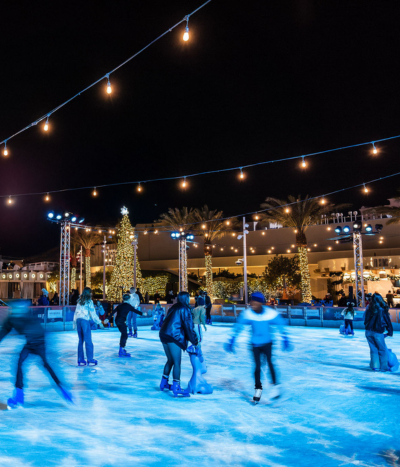 People ice skating with holiday decorations in the background