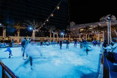 People ice skating with holiday decorations in the background