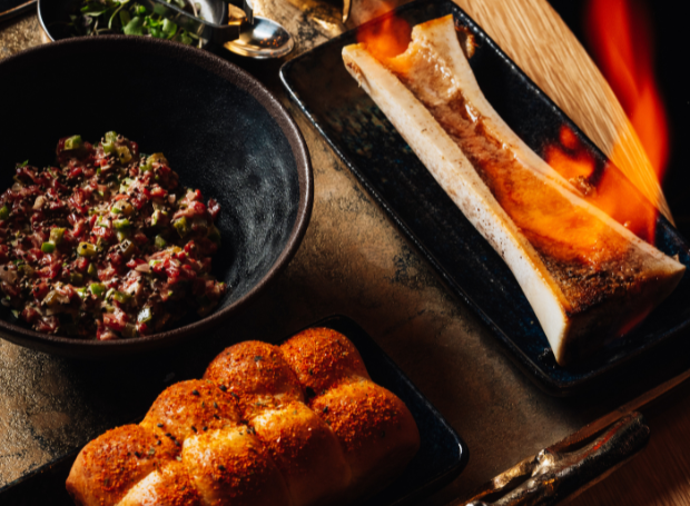 Flaming bone marrow and food on a table
