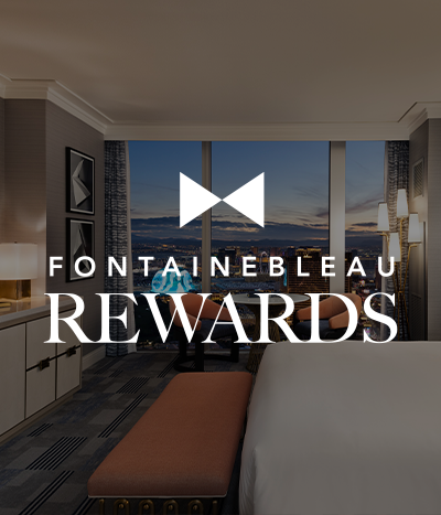 Bed and seating area under text: Fontainebleau Rewards