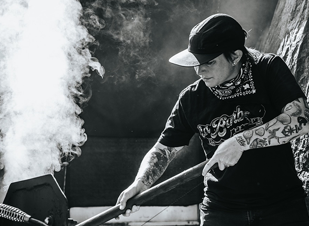 Pitmaster stoking a fire in black and white