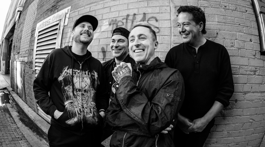 4 band members in black and white against a brick wall