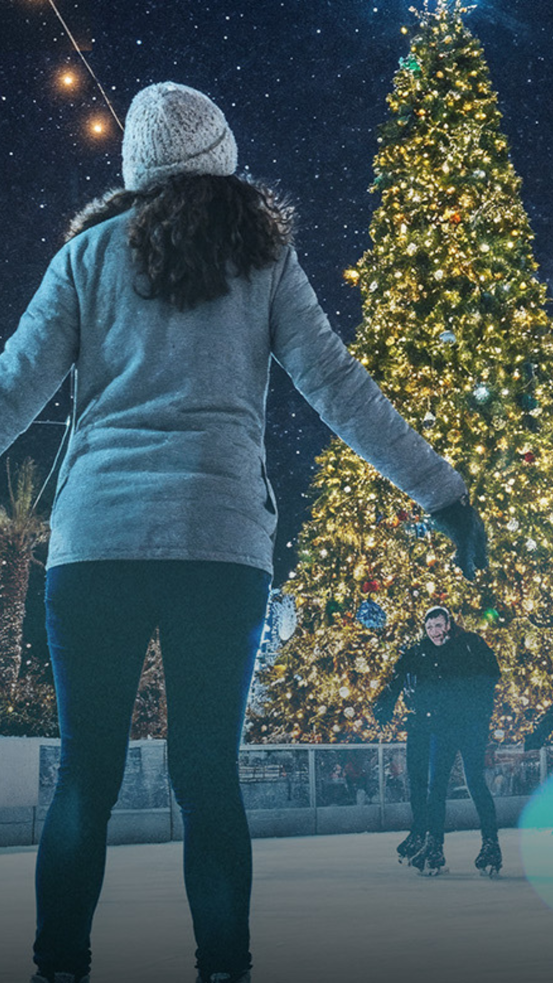Ice skater looking up at a holiday tree