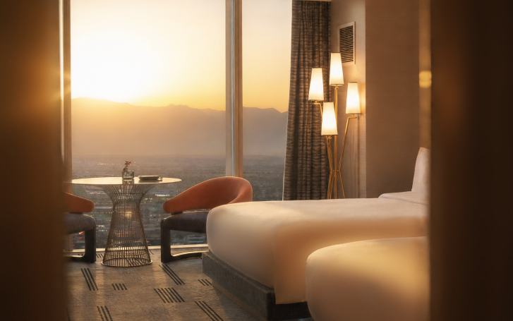 Relaxing warm Fall sunset view from beautiful room overlooking the Las Vegas Strip with two queen beds, table with floor to ceiling windows and dim lit lights